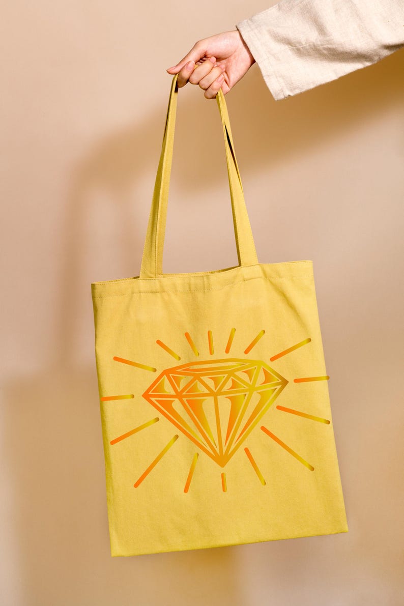 May include: A yellow canvas tote bag with a large, orange and yellow diamond graphic. The diamond is surrounded by sun rays.