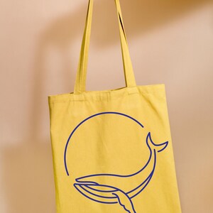 May include: A yellow tote bag with a blue whale outline design. The whale is inside a circle.