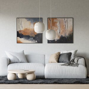 Peut inclure: Un canap&eacute; sectionnel blanc avec deux coussins et une couverture se trouve devant un mur avec deux tableaux abstraits et une plante en pot. Une table basse ronde &agrave; trois pieds se trouve devant le canap&eacute;.