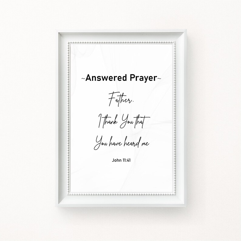May include: A framed print with the text "~Answered Prayer~ Father. I Thank You that You have heard me" and the Bible verse John 11:41. The text is in black script on a white background, framed in a white frame.