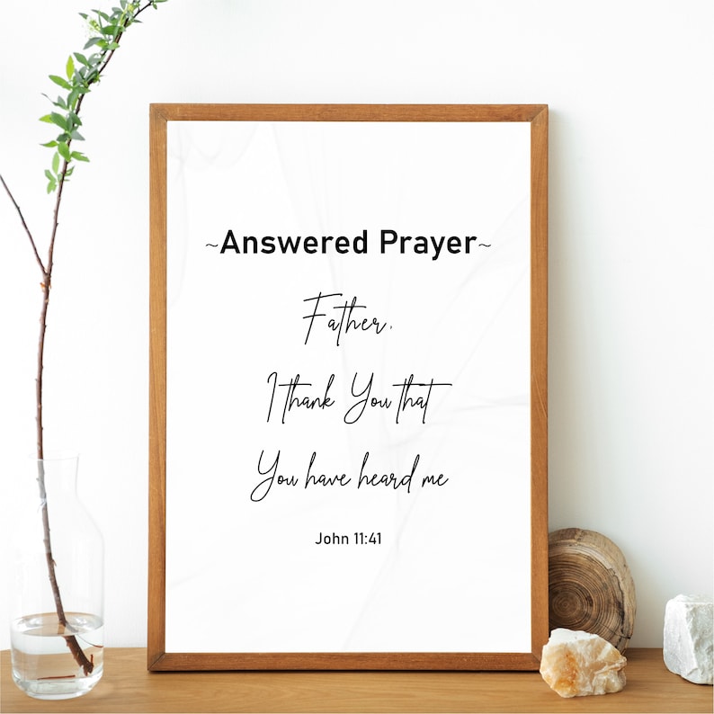 May include: A framed print with the text "~Answered Prayer~ Father. I Thank You that You have heard me John 11:41" in a script font. The frame is a medium brown color, and the background is white with a subtle marbled design.