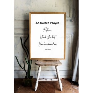 May include: A framed print with a wooden frame displays the text "Answered Prayer" and a prayer. The text is in black on a white background. The print is displayed on a small wooden stool.
