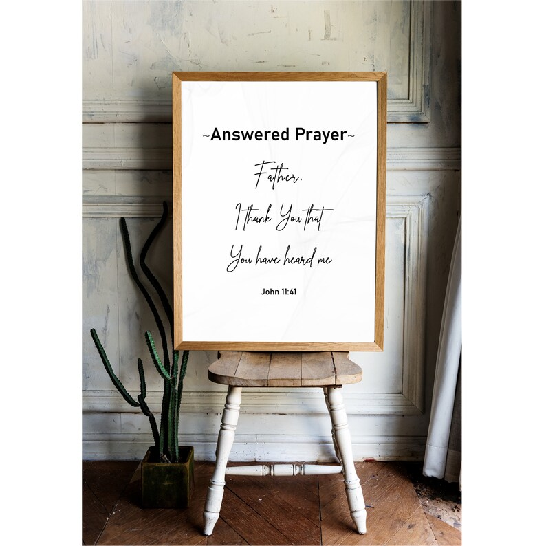 May include: A framed print with a wooden frame displays the text "Answered Prayer" and a prayer. The text is in black on a white background. The print is displayed on a small wooden stool.