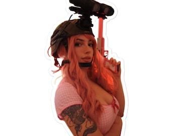 May include: A woman wearing a pink and white checkered top and a black helmet with a scope attached to it. She is holding a pink toy gun in her right hand. She has pink hair and a black dragon tattoo on her left arm.