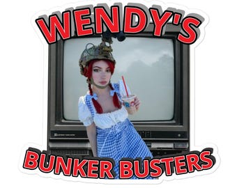 May include: A sticker featuring a person in a Dorothy costume, wearing a military helmet, and holding a drink in front of an old television. The sticker has the words "WENDY'S" and "BUNKER BUSTERS" in red and white.