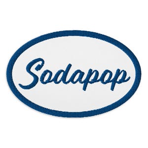 May include: A white oval patch with a blue border and the word "Sodapop" embroidered in blue cursive lettering.