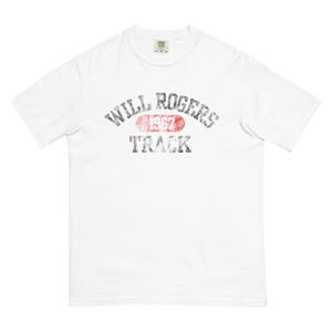 May include: White t-shirt featuring a distressed graphic design. The graphic says "WILL ROGERS TRACK 1967" in a vintage style. The text is in black and red, with a faded look, giving it a retro feel.