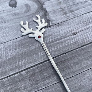 May include: Silver reindeer stirring spoon with a red rhinestone for the nose and the name "Ariella" engraved on the handle.