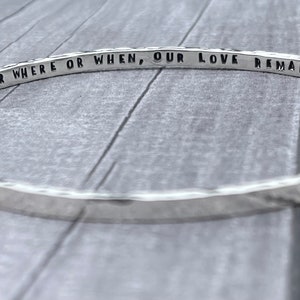 May include: Silver bangle bracelet with the inscription "No matter where or when, our love remains x".
