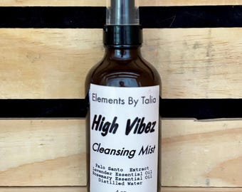 May include: A brown glass bottle with a black spray top. The bottle is labeled "Elements By Talia High Vibez Cleansing Mist" and lists the ingredients: Palo Santo Extract, Lavender Essential Oil, Rosemary Essential Oil, Distilled Water. The bottle contains 4 ounces of liquid.