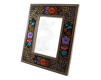 Puede incluir: Marco de fotos rectangular con diseño floral. El marco tiene un fondo negro con filigranas doradas y flores coloridas en tonos rojos, naranjas, morados y azules. El marco es de madera y tiene un borde dorado.