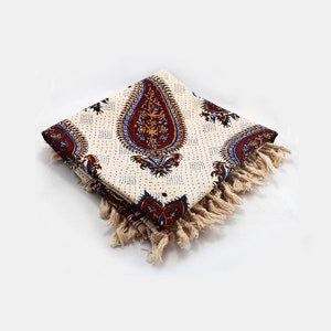May include: A white cotton throw blanket with a paisley pattern in shades of red, blue, and yellow. The blanket has a fringe border.