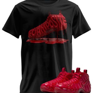 May include: A black short-sleeve t-shirt featuring a graphic of a red sneaker with the word FOAMPOSITE written in a dripping, liquid-like font. Below the shirt, a pair of matching red high-top sneakers with laces and a side swoosh logo.