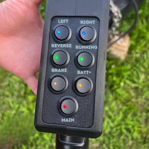 May include: Black control panel with seven illuminated buttons labeled "LEFT", "RIGHT", "REVERSE", "RUNNING", "BRAKE", "BATT+", and "MAIN". The buttons have blue, green, orange, and red lights.