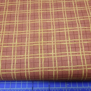 May include: A close-up of a fabric with a brown background and a yellow grid pattern.