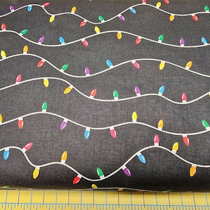 Puede incluir: Tela negra con una cadena de bombillas de colores impresas en blanco. Las luces están en un patrón ondulado.