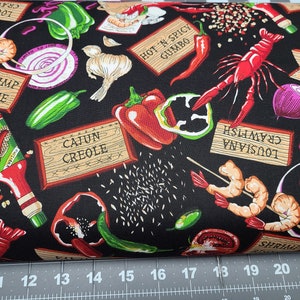 Puede incluir: Tela negra con un estampado colorido con elementos de la cocina cajún y criolla. El diseño incluye camarones, cangrejos de río, pimientos, cebollas, ajo y etiquetas como "Cajun Creole" y "Hot 'N Spicy Gumbo."