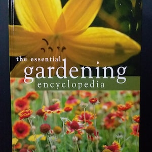 Puede incluir: La portada del libro The Essential Gardening Encyclopedia presenta una flor amarilla con un fondo verde. La parte inferior de la portada muestra un campo de flores rojas y amarillas.