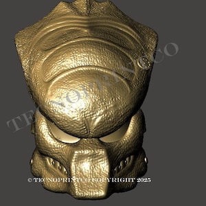 May include: A gold-colored Predator mask, featuring detailed textures and a menacing design. The mask has a distinct shape with prominent features, including a textured forehead, eye sockets, and a detailed lower jaw. The image includes the text "TECNOPRINTCO COPYRIGHT 2023".