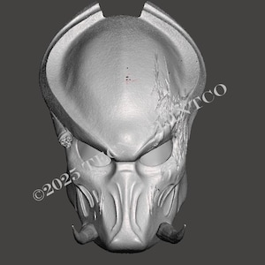 May include: A detailed, grayscale 3D model of a Predator mask, featuring intricate sculpted details. The mask has a distinctive helmet shape with a prominent brow, eye sockets, and a textured surface. The image includes the text "©2025 TXTCO".