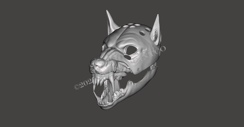 May include: A gray, three-dimensional digital render of a wolf mask featuring pointed ears, a snout with bared teeth, and a series of circular perforations along the top. The design includes a hinged jaw structure and visible eye openings.