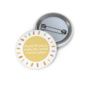 May include: A white button with a yellow sun design and the text "Social Workers make the world a better place".
