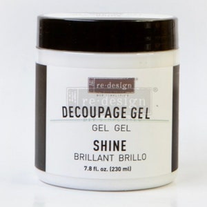 K&ouml;nnte beinhalten: Ein wei&szlig;es Glas re-design Decoupage Gel mit schwarzem Deckel. Das Etikett lautet "re-design Decoupage Gel, Gel Gel, Shine, Brillant Brillo, 7.8 fl. oz. (230 ml)"