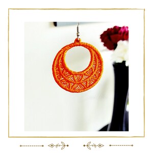 May include: Orange crocheted hoop earrings with a delicate, intricate design. The earrings are made with a single strand of yarn and have a simple, elegant look.