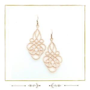 May include: A pair of delicate, cream-colored earrings with a intricate, knotted design. The earrings are made of a thin, woven material and have a dangling, teardrop shape.