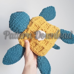 May include: A crocheted turtle toy with a blue shell and yellow body. The turtle has a white patch on its shell.