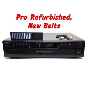 May include: A black Sony 5-disc CD changer with a digital display, control buttons, and a disc tray. The unit includes a black remote control and an RCA audio cable. Text on the unit reads 5 CD CHANGER Disc Ex-change System. Pro Refurbished, New Belts.
