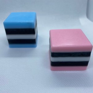 May include: Two square-shaped soaps, one blue and one pink, with black and white stripes.