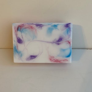 May include: A white bar of soap with swirls of blue, purple, and pink.