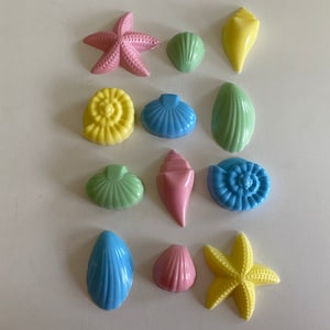 May include: A collection of pastel-colored chocolate seashells and starfish. The shells are in shades of blue, green, pink, and yellow. The starfish are yellow.