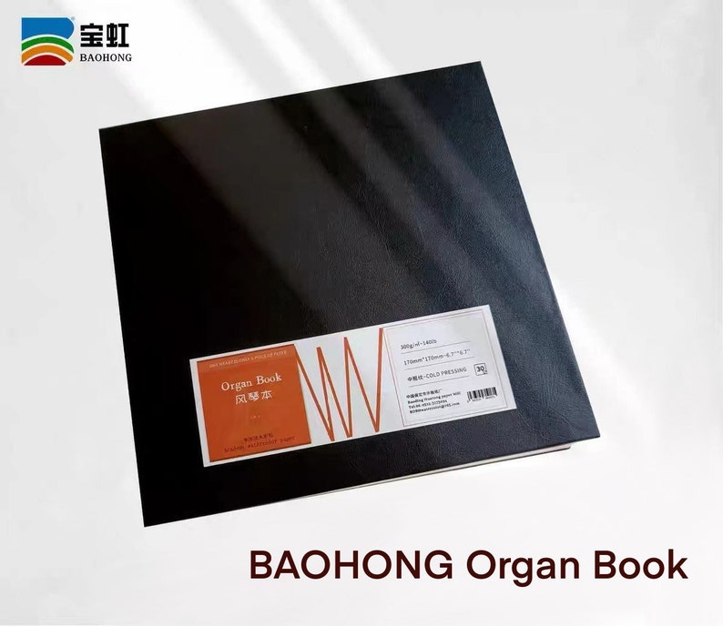 May include: A black, square, hardcover book with the text "Organ Book" in red and Chinese characters on the front cover. The book is labeled "200g/m&sup2; - 140S" and "170mm*170mm - 4.2"*4.2" - 中性 - COLD PRESSING" on the right side. The book is on a white surface.