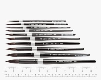 May include: A collection of Silver Black Velvet watercolor paint brushes of varying sizes, arranged in a row. The brushes have black handles with silver accents and dark bristles. A ruler is at the bottom, with measurements in inches.
