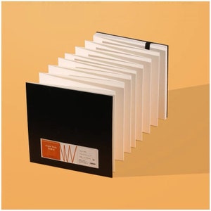 May include: A black sketchbook with a white paper pad inside. The sketchbook has a red and white label that says "Organik Book 150 gsm".