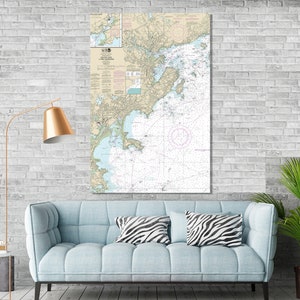 May include: A nautical chart of the Boston Harbor and its surrounding waters. The chart is printed on paper and features detailed information about the area, including depths, buoys, and other navigational aids. The chart is framed and hanging on a white brick wall above a light blue sofa with zebra print throw pillows.