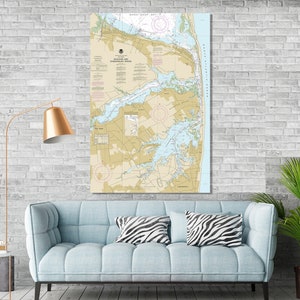 May include: A nautical chart of the waterways in and around the town of Ocean City, Maryland. The chart is printed on a beige background with blue and green lines and text. The chart includes a compass rose, depth soundings, and navigational aids.