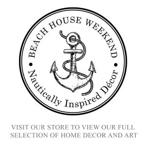 以下が含まれることがあります： 黒と白の円形ロゴ。錨のイラストと「Beach House Weekend, Nautically Inspired D&eacute;cor」の文字。下には「当店のホームデコとアートのフルセレクションをご覧ください」と書かれています。