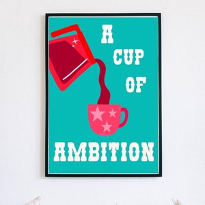 May include: A framed art print with a teal background and the words "A CUP OF AMBITION" in white. A red container pours a dark red liquid into a pink mug decorated with stars. The artwork is in a black frame.