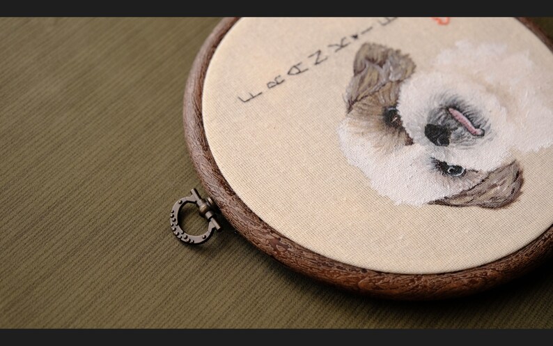May include: Embroidered portrait of a white dog with brown markings in a wooden embroidery hoop. The hoop has a metal clasp and the fabric is beige. The text "Forever" is embroidered above the dog.