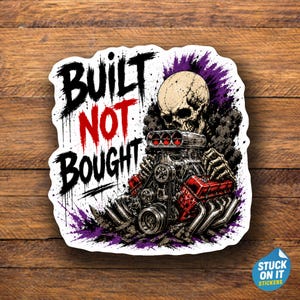 May include: A die-cut sticker featuring a human skull with skeletal hands gripping a large, detailed V8 engine with red valve covers. The text BUILT NOT BOUGHT is printed in black and red, with purple and black smoke accents surrounding the engine.