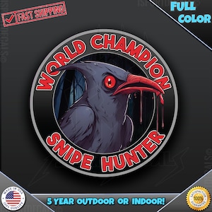 May include: A black and red circular sticker with the text "World Champion Snipe Hunter" in a white circle. A cartoon crow with red eyes and a bloody beak is in the center of the sticker.