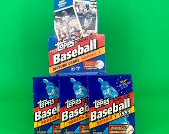 May include: Stacked boxes of 1993 Topps Major League Baseball Series 1 trading cards. The boxes are blue, red, and yellow with images of baseball players and the Topps logo. The background is a solid green.
