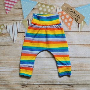 May include: Rainbow striped baby pants with a wide elastic waistband. The pants are made of soft, comfortable fabric and have a relaxed fit.