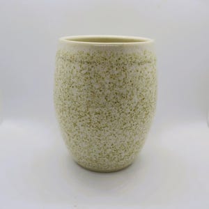 May include: A white ceramic vase with a speckled green glaze. The vase has a rounded shape and a smooth, matte finish.