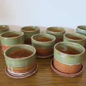 Rustic ceramic planters with catchers.  Top half green, bottom and catchers terracotta.