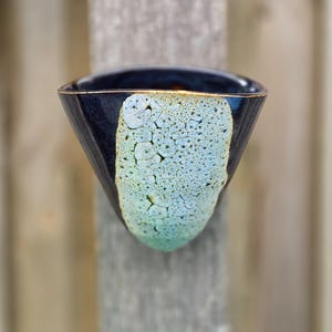 May include: A dark blue ceramic bowl with a light blue and white crackle glaze. The bowl has a unique, asymmetrical shape.