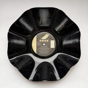 May include: A black vinyl record bowl with a scalloped, wavy edge. The center label is circular, black, and gold, featuring the Wing Records logo and the text Tony! Toni! Toné! along with track listings and production credits in white text.